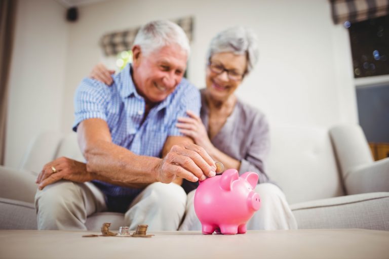 Altes Ehepaar wirft Geld in eine Spardose